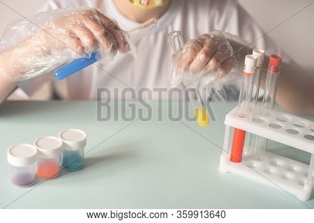 A Child In A White T-shirt In The Laboratory Is Studying Chemistry . Young Scientists In Protective 