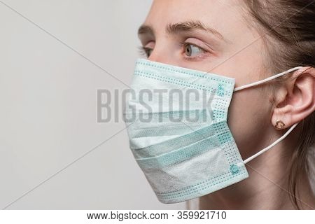 Young Woman Wearing Surgical Mask With Ear Rubber Straps. Portrait Close Up Side View.