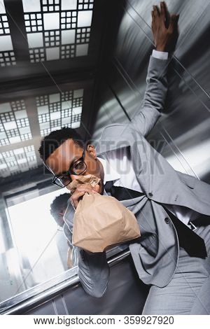 Stressed African American Businessman Breathing With Paper Bag And Suffering From Panic Attack In El