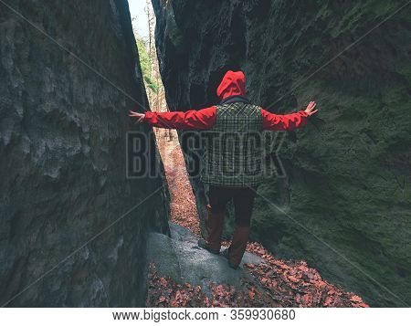 Woman Goes Through Thin Pass Between Sandstone Rocks.