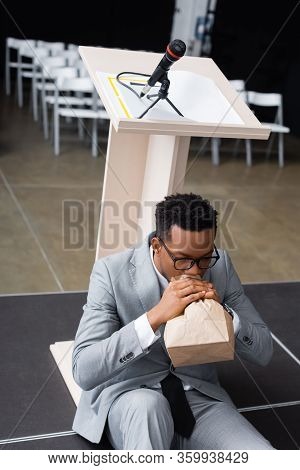 Scared African American Speaker Breathing With Paper Bag And Having Panic Attack Before Business Con