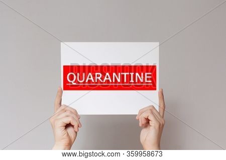 Hands Hold A  Sheet. A Sign That Says Quarantine