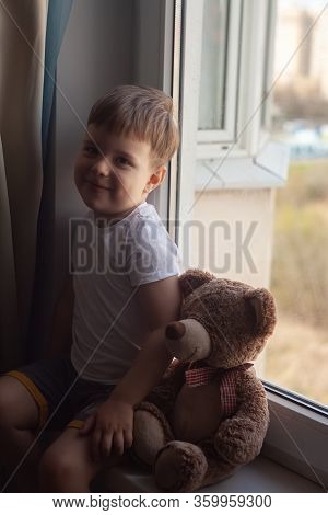 Stay At Home Quarantine Coronavirus Prevention Of The Pandemic. A Child And His Teddy Bear On The Wi