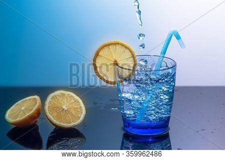A Mug Of Ice And Water Sits On A Mirrored Table With Sliced Lemons.preparation Of A Fresh Drink Toni
