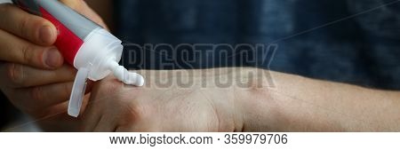 Close-up Of Person Applying Handcream From Plastic Tube On Hand. Moisturizing Sensitive Skin. Beauty