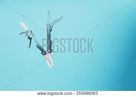 The Multitool Multi-function Tool Hovers On A Blue Background. The Concept Of An Expanded Multi-tool