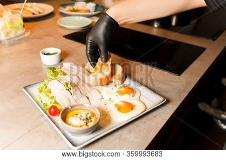 Chef Preparing Healthy Food In Kitchen In The Restaurant. Breakfast. Fried Eggs, Salad With Meat And