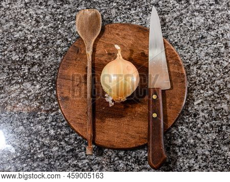 Preparing Items For Cooking An Onion Tart As A Wooden Spoon, A Knife And An Onion.
