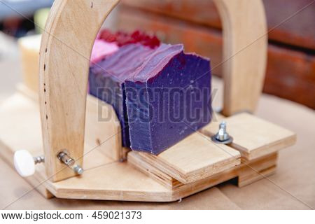 Wooden Device For Cutting Soap Handmade With A Freshly Cut Purple Bar Of Soap. Close Up