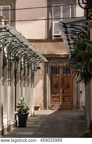Narrow Alley Leading To A Wooden Door - Seen In Lucca Tuscany