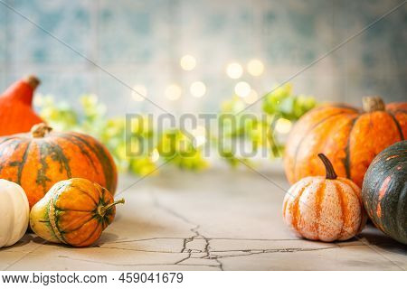 Thanksgiving Or Halloween Autumn Decorations With Mini Green And Orange Pumpkins Against A Tile Back