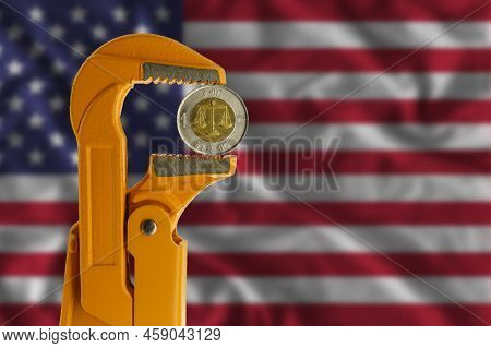 Ethiopian One Birr Coin Held In An Orange Plumber Wrench On The Background Of The Flag Of The United