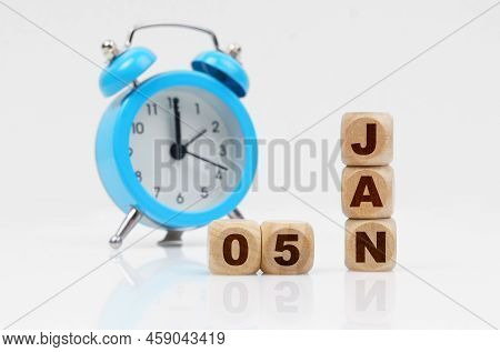 5st Of January. Wooden Cube Calendar For January 5, Next To A Blue Alarm Clock. Objects On A Reflect