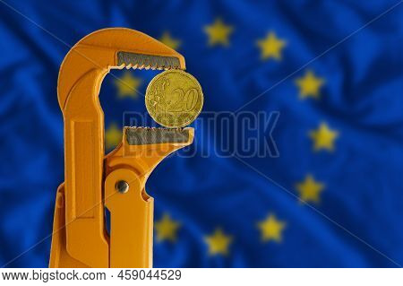 20 Euro Cent Coin Held In An Orange Plumber Wrench On The Background Of The European Flag. Reverse O