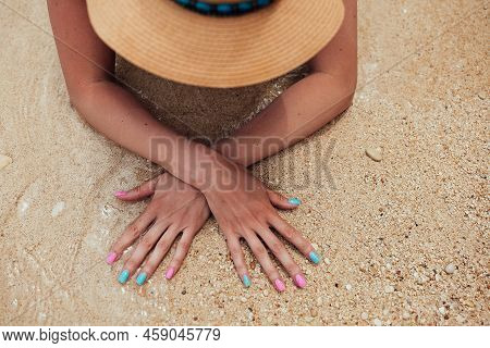 Beautiful Female Hands With Pink And Blue Manicure Nails On Sea Sand Background