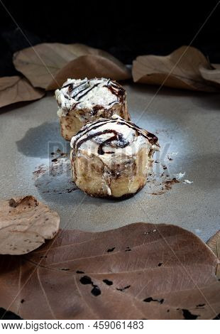 Two Cinnabon Chocobon (soft Chocolate Buns) Topped With Rich Cream Cheese Frosting On Ceramic Tray W