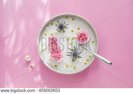 Top View Of The White Plate With Spoon, Milk And Pink, White And Blue Flowers, On Pink Background Wi
