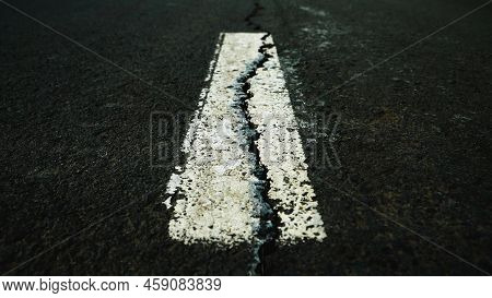 Worn White Road Line On Cracked Asphalt Close-up
