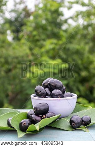 Jamun Or Syzygium Cumini In A Bowl With Leaves Isolated On Wooden Background, Also Known As Java Plu