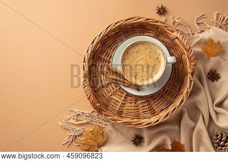Autumn Concept. Top View Photo Of Wicker Basket With Cup Of Frothy Coffee On Saucer Cinnamon Sticks 