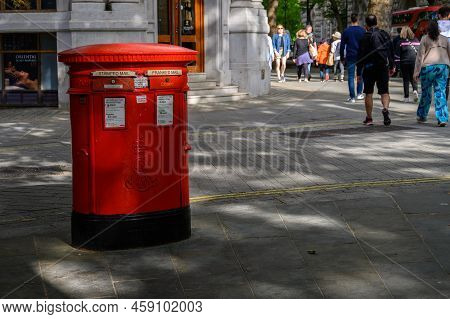 London - May 16, 2022: Traditional British Red Postbox With People Passing By In The Background