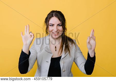 Young Beautiful Woman Shows Ok Jesture, Bright Yellow Background