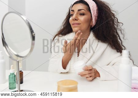 Enjoyed Tanned Pretty Curly Latin Lady Admiring Herself In Mirror Use Facial Cream Do Beauty Procedu