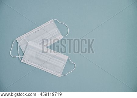 Tipical Surgical Masks With Rubber Ear Straps On Blue Background, Top View . Protection Concept.