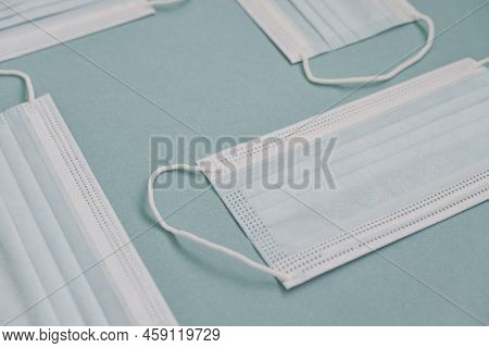 Tipical Surgical Masks With Rubber Ear Straps On Blue Background, Top View . Protection Concept.