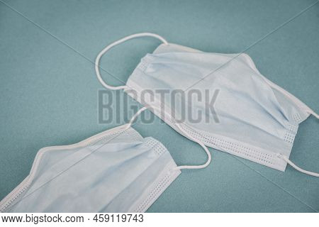 Tipical Surgical Masks With Rubber Ear Straps On Blue Background, Top View . Protection Concept.