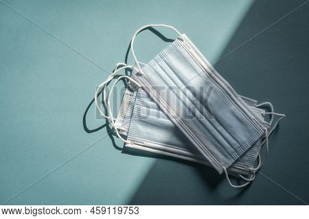 Tipical Surgical Masks With Rubber Ear Straps On Blue Background, Top View . Protection Concept.
