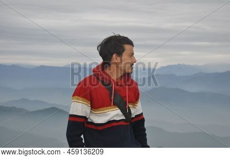 Waist Up Of A Good Looking Indian Young Guy Looking Sideways While Standing Against The Background O