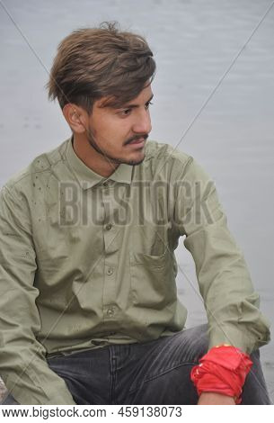Close Up Of A Good Looking Young Guy Looking Sideways While Sitting Next To The Lake
