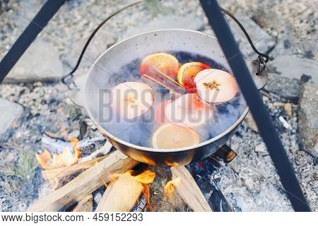 From Above Traditional Mulled Wine With Slices Of Orange Preparing In Pot Over Burning Logs In Winte