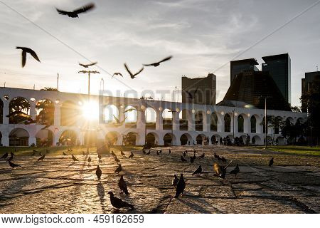Sun Shines Through Lapa Arches In Rio De Janeiro With Pigeons Flying In Front Of It