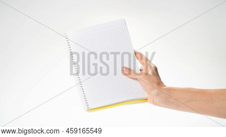 A Womans Right Hand Holds A Notebook In A Cage On A White Background Space For Inscription. High Qua