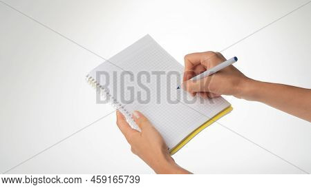 Womens Hands Hold A Notebook, A Pen In Her Right Hand Writes In A Notebook In A Cage. High Quality P