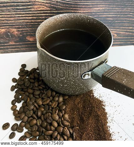 Coffee Beans, Ground Coffee And Coffee Cezve. The Photo Shows Coffee Beans And Ground Coffee. Nearby