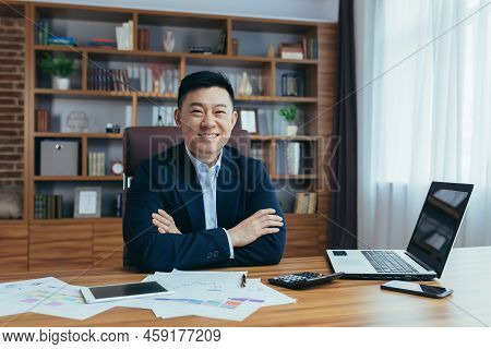 Portrait Of A Young Handsome Asian Man, Businessman, Boss In A Suit, Sitting In A Chair At A Table I