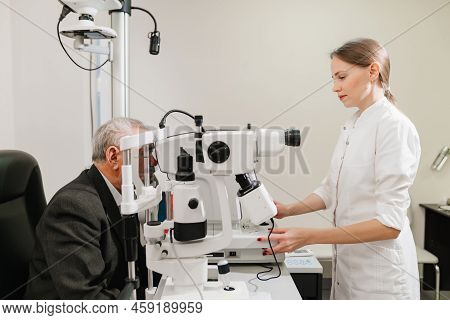 Doctor Examines Elderly Mans Eye On Screen Of Autorefractometer.