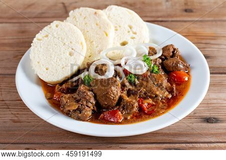 Czech Traditional Goulash With Breaded Dumpling And Onion On White Plate On Wooden Table