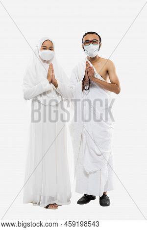 Couple Wearing Hajj Ihram Clothes And Masks With Greeting Gesture