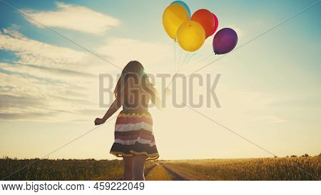 Little Girl Runs With Balloons In The Park In Nature. Happy Family Holiday Birthday Kid Dream Concep