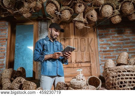 Male Entrepreneur In Hat Using Tablet Standing Close To Craft
