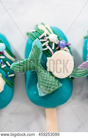 Mermaid Cakesicles With Drizzled Chocolate, Chocolate Mermaid Tails, Seashells, And Sprinkles.