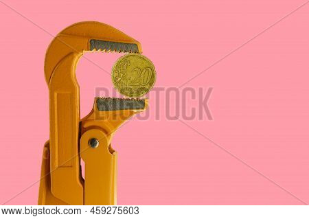 20 Euro Cent Coin Held In An Orange Plumber Wrench On A Pink Background. Reverse Of The Coin.