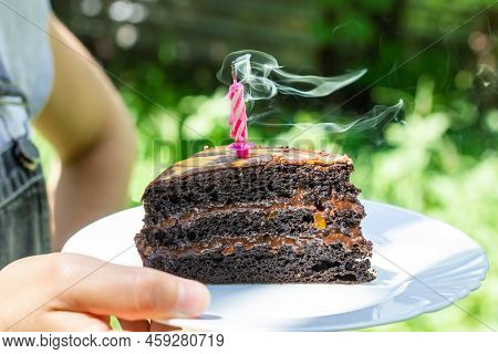 A Piece Of Birthday Cake. A Blown Out Candle In A Piece Of Cake. Smoke From A Blown Out Candle.