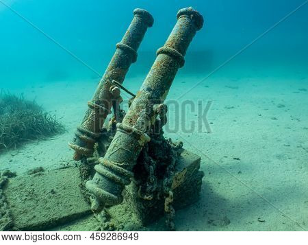 Antique Cannons On A Sandy Sea Floor. Beautiful Turquoise Water In The Background