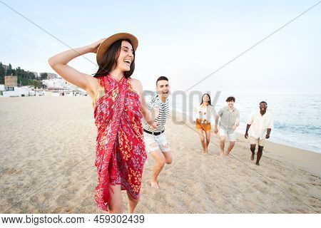 Happy Group Of Young People Having Fun Running At The Beach. Funny Friends Feeling Freedom And Frien