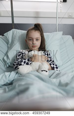 Sick Little Girl Under Treatment Wearing Oxygen Tube While Holding Plush Bear Toy. Ill Kid Resting I